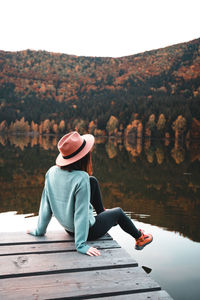 Rear view of woman sitting on pier