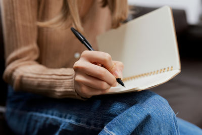 Midsection of woman writing in book