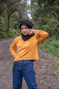 Portrait of young woman wearing hat standing on field
