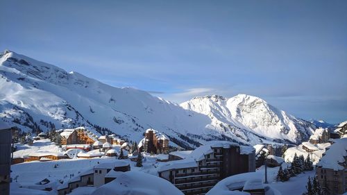 Houses on snowcapped mountain against sky