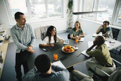 High angle view of smiling multiracial business colleagues planning during meeting in office