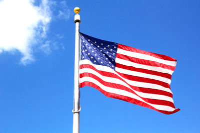 Low angle view of american flag against blue sky