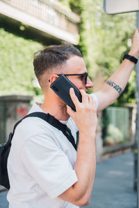 Young man talking over phone while standing in city