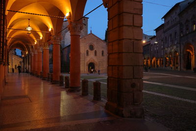 Illuminated street amidst buildings in city at night