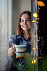 Portrait of woman holding coffee cup at home