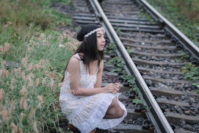 Young woman sitting on railroad track