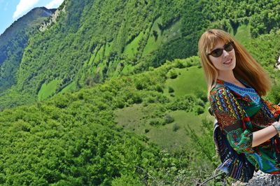 Portrait of young woman standing on green landscape