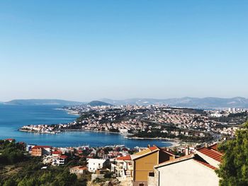 High angle view of townscape by sea against clear sky