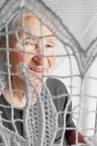 Portrait of smiling senior woman looking through fabric