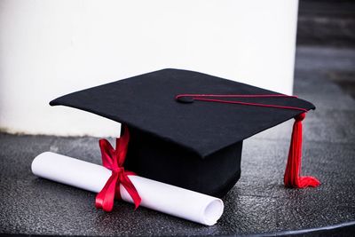 High angle view of mortarboard and diploma on table