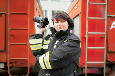 Smiling firefighter holding camera outdoors