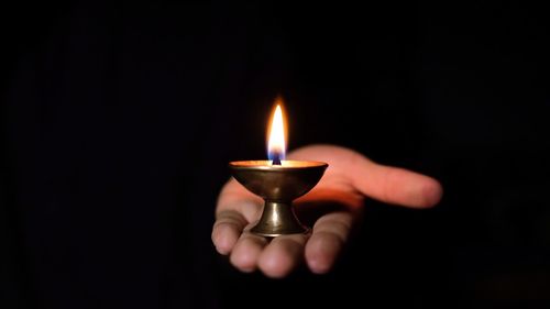 Close-up of human hand holding burning candle