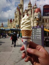 Cropped hand holding ice cream cone in city