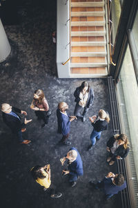 High angle view of business people discussing while standing at workplace