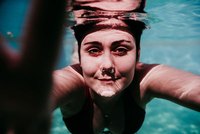 Portrait of woman swimming underwater in pool