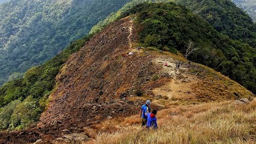 Rear view of people standing on mountain against sky