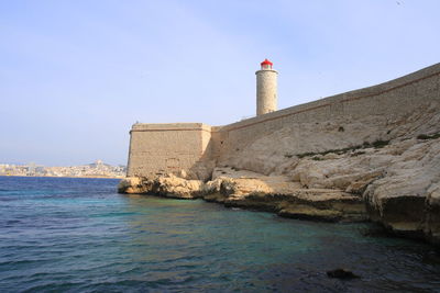 Lighthouse by sea against sky