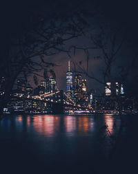 Illuminated buildings by river at night