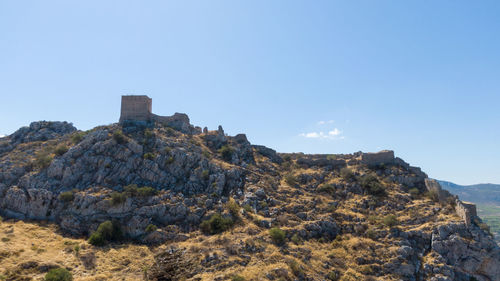 Low angle view of rocks on mountain against clear sky