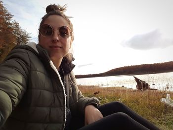 Portrait of woman sitting in sunglasses against sky