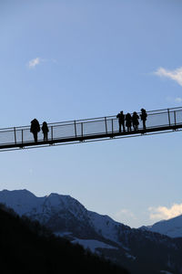 Silhouette people on bridge against sky