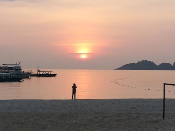 Silhouette people on calm beach at sunset