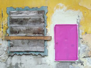 Closed window between pink door of old building