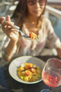 Beautiful young girl tasting a delicious risotto with smoked salmon