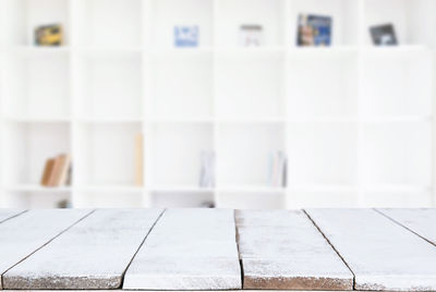 Empty wooden table against white bookshelf at home