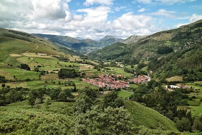 Scenic view of green landscape and mountains against sky