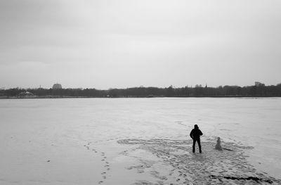 Rear view of man on land against sky during winter