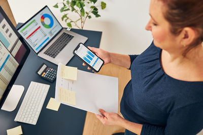 Businesswoman working with financial data on charts. woman looking at stats on smartphone. office