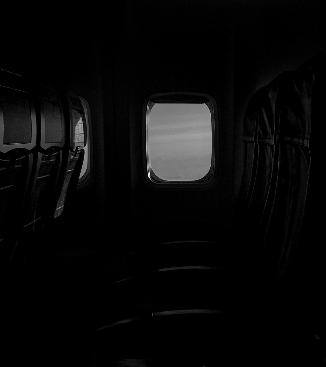 black, darkness, black and white, mode of transportation, light, transportation, vehicle interior, monochrome, monochrome photography, airplane, white, window, indoors, air vehicle, no people, public transportation, travel, vehicle, dark, vehicle seat, seat, automotive exterior, in a row, lighting