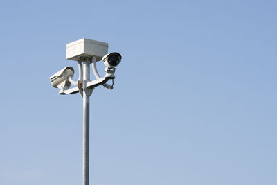 Low angle view of security cameras against sky