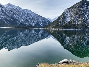 Scenic view of lake by snowcapped mountains against sky