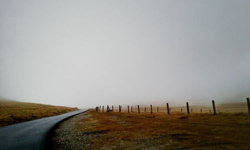 Road amidst field against clear sky