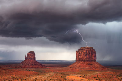 Lightning strikes merrick butte as a thunderstorm drifts through monument valley, arizona.