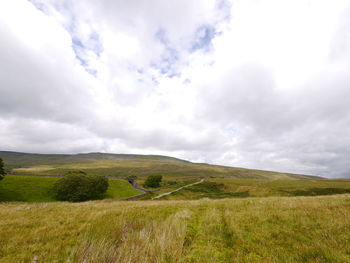Scenic view of field against cloudy sky