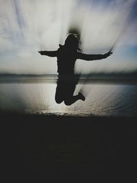 Silhouette man jumping in water against sky