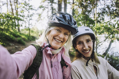 Portrait of happy senior women taking selfie wearing cycling helmet