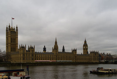 View of buildings by river against sky in city