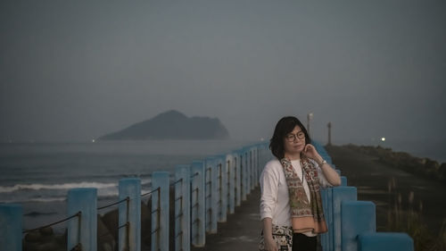 Portrait of young woman standing against sea