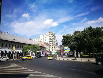 Road by trees against sky in city