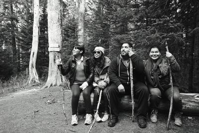 Full length of female friends standing on tree stump