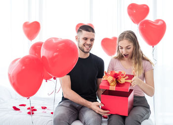 Young couple with red balloons in box