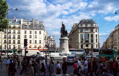 People in city against cloudy sky