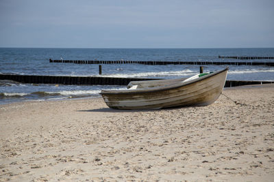 Boat moored on beach against sky