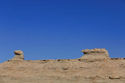 Low angle view of rock formations against clear blue sky