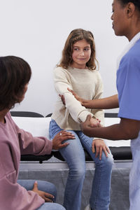 Female doctor examining girl patient's arm