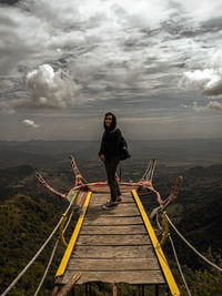 Full length of man standing on railing against sky